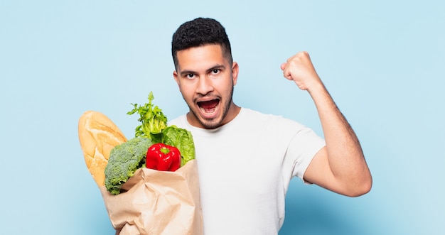 Jeune homme hispanique célébrant une victoire réussie. concept d'achat de légumes