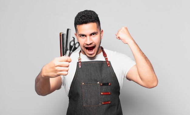 jeune homme hispanique célébrant une victoire réussie. concept de barbier