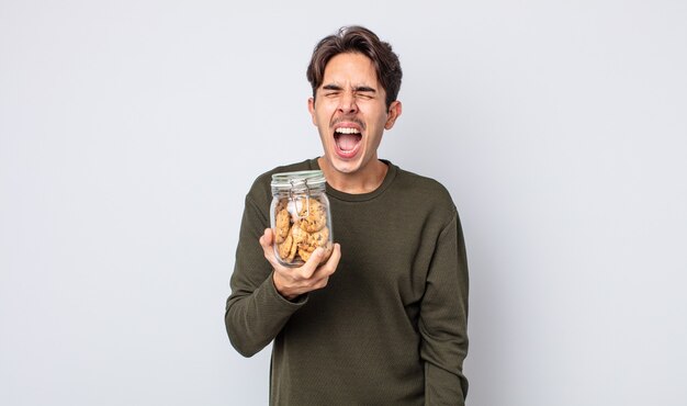 Jeune homme hispanique criant agressivement, l'air très en colère. notion de cookies