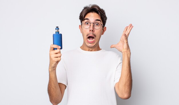 Jeune homme hispanique criant avec les mains en l'air. concept de vaporisateur de fumée