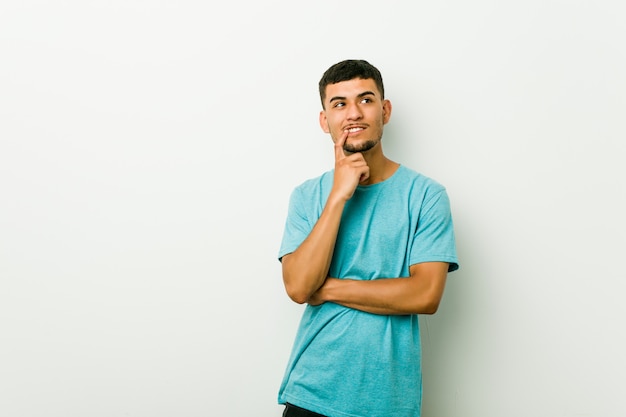 Jeune homme hispanique détendu en pensant à quelque chose en regardant un espace de copie.