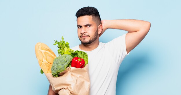 Jeune homme hispanique doutant ou expression incertaine. concept d'achat de légumes