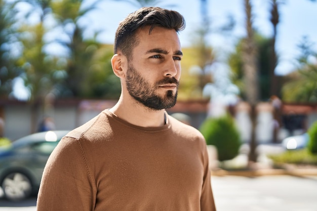 Jeune homme hispanique avec une expression détendue debout au parc