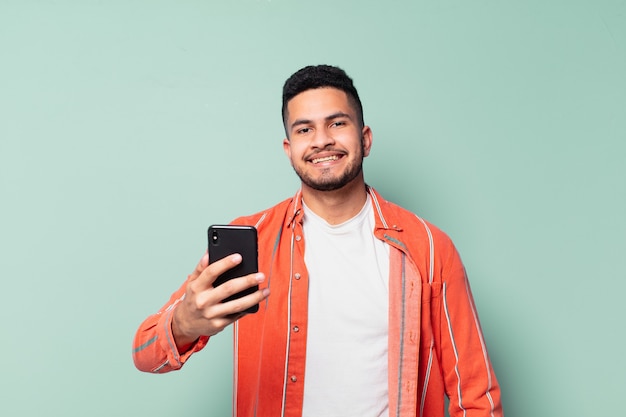 Jeune homme hispanique expression heureuse et tenant un téléphone portable