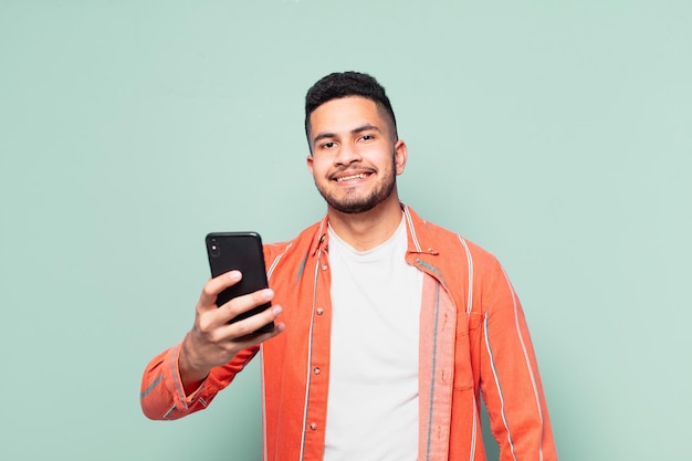 Jeune homme hispanique expression heureuse et tenant un téléphone portable