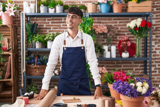 Jeune homme hispanique fleuriste souriant confiant debout chez fleuriste