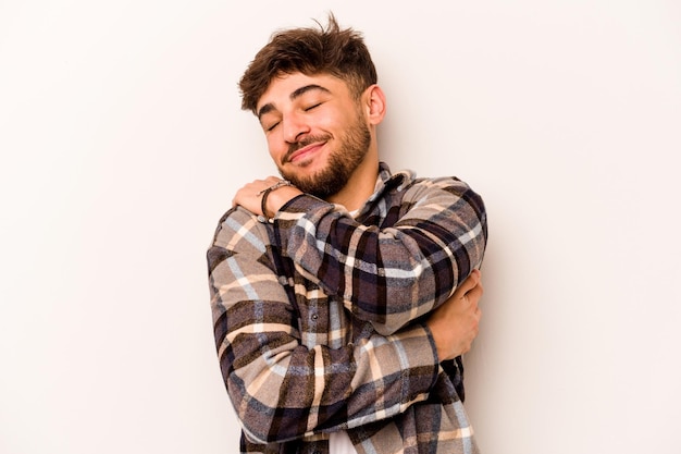 Jeune homme hispanique isolé sur fond blanc câlins souriant insouciant et heureux