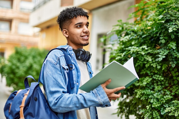 Jeune homme hispanique lisant un livre dans la rue