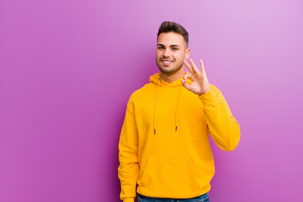 Jeune homme hispanique avec un look décontracté sur fond violet