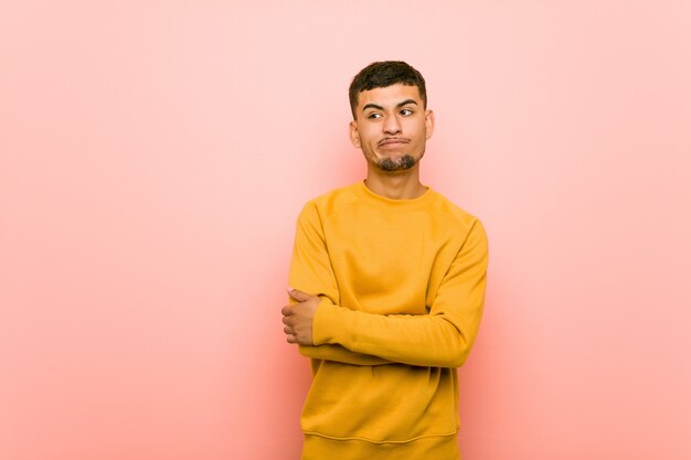 Jeune homme hispanique malheureux regardant à huis clos avec une expression sarcastique.