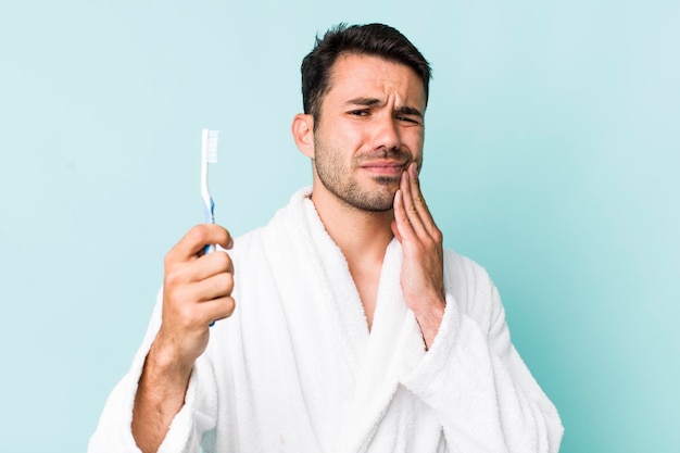 Jeune homme hispanique peignoir et concept de brosse à dents