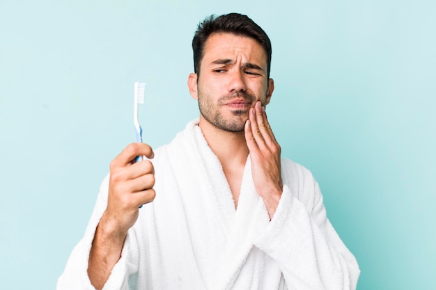 Jeune homme hispanique peignoir et concept de brosse à dents