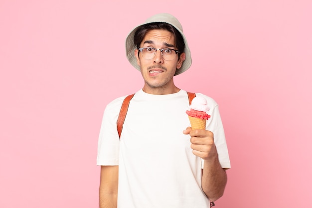 Jeune homme hispanique à la perplexité et confus et tenant une glace