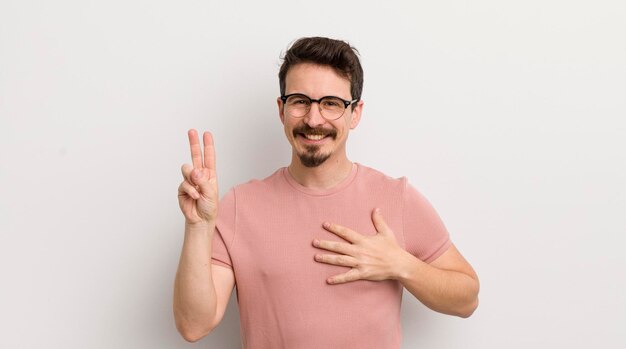 Un jeune homme hispanique qui a l'air heureux, confiant et digne de confiance, souriant et montrant le signe de la victoire avec une attitude positive