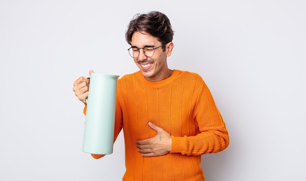 Jeune homme hispanique riant aux éclats d'une blague hilarante. concept thermos