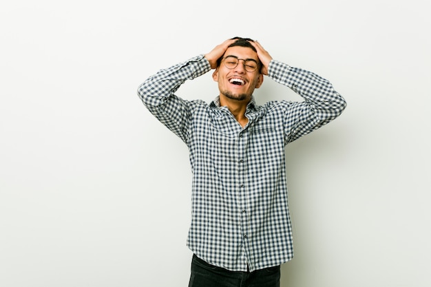 Jeune homme hispanique rit joyeusement en gardant les mains sur la tête. Concept de bonheur.