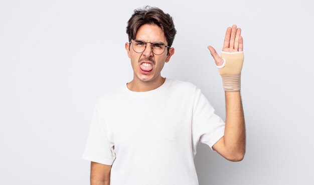 jeune homme hispanique se sentant dégoûté et irrité et tirant la langue. concept de bandage à la main