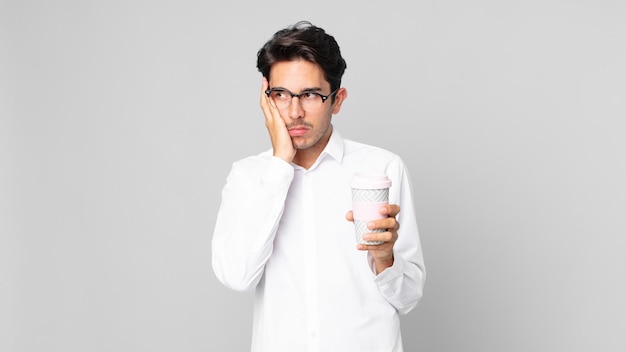 Jeune homme hispanique se sentant ennuyé, frustré et somnolent après un fastidieux et tenant un café à emporter