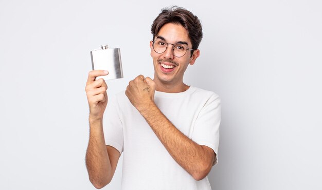 Jeune homme hispanique se sentant heureux et faisant face à un défi ou célébrant le concept de flacon d'alcool