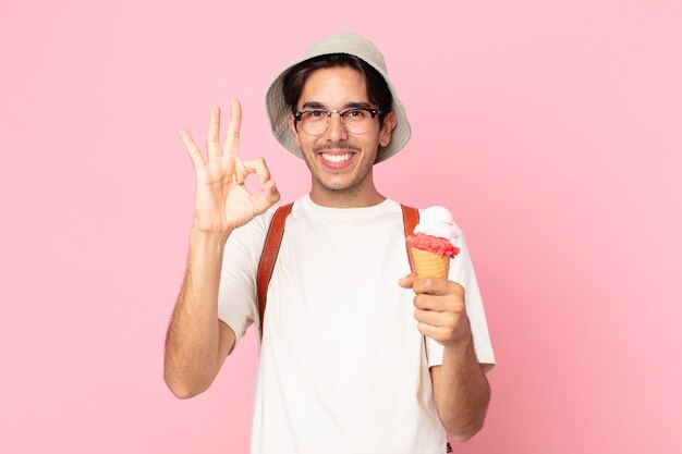 Jeune homme hispanique se sentant heureux, montrant son approbation avec un geste correct et tenant une glace