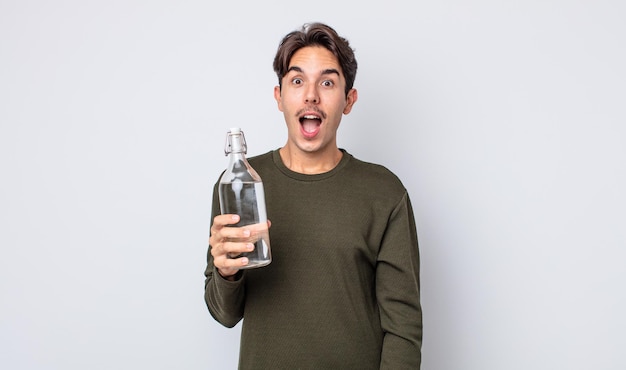 Jeune homme hispanique semblant très choqué ou surpris. notion de bouteille d'eau