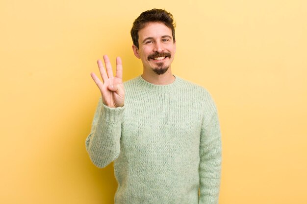 Jeune homme hispanique souriant et amical montrant le numéro quatre ou quatrième avec la main en avant compte à rebours