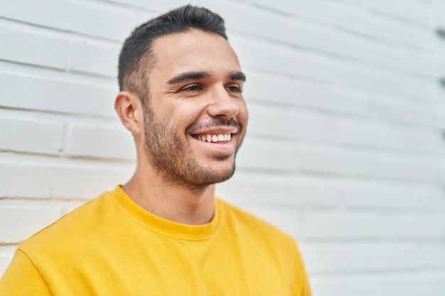 Jeune homme hispanique souriant confiant regardant sur le côté sur fond blanc isolé