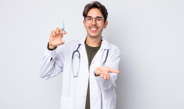 Jeune homme hispanique souriant joyeusement avec amicalement et offrant et montrant un concept. concept de seringue de médecin