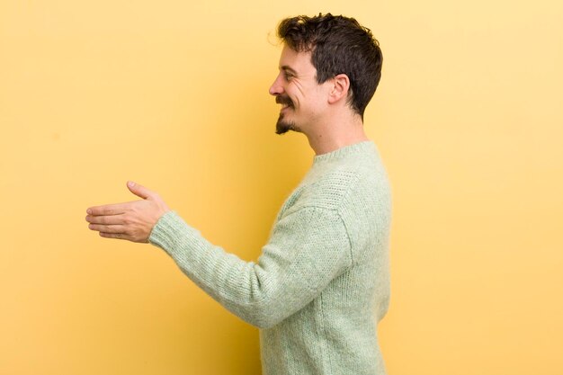 Jeune homme hispanique souriant vous saluant et offrant une poignée de main pour conclure un concept de coopération réussi