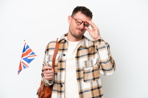 Jeune homme hispanique tenant un drapeau du Royaume-Uni isolé sur fond blanc avec des maux de tête