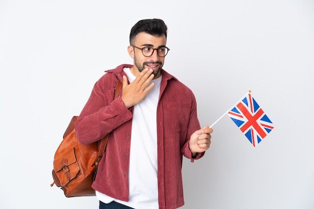 Jeune homme hispanique tenant un drapeau du Royaume-Uni à la recherche en souriant