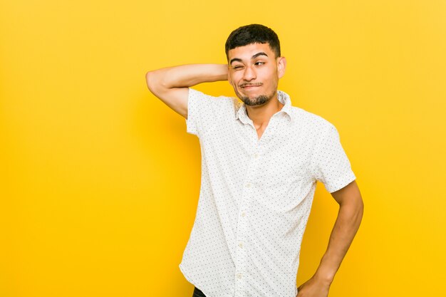 Jeune homme hispanique touchant l'arrière de la tête, réfléchissant et faisant un choix.