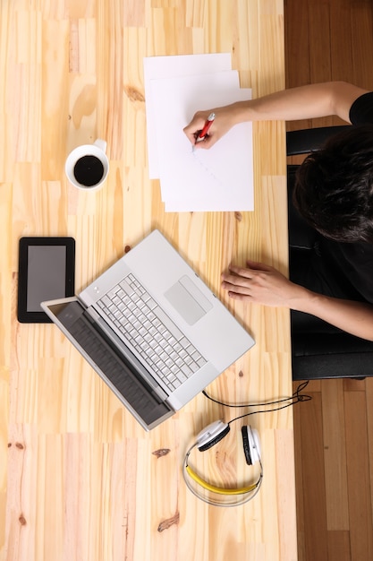 Un jeune homme hispanique travaillant sur un bureau en bois avec un ordinateur portable.