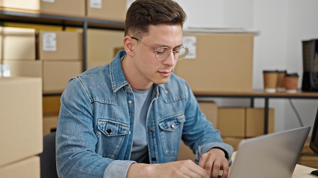 Jeune homme hispanique travaillant dans le commerce électronique à l'aide d'un ordinateur portable assis sur une table au bureau