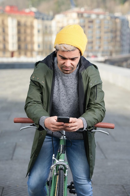 Jeune homme hispanique à vélo à l'aide de téléphone