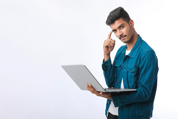 Jeune homme indien à l'aide d'ordinateur portable sur fond blanc.