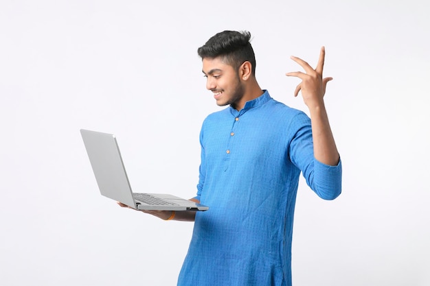 Jeune homme indien à l'aide d'ordinateur portable sur fond blanc.