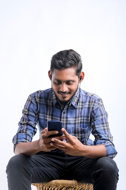 Jeune homme indien à l'aide de smartphone sur fond blanc.