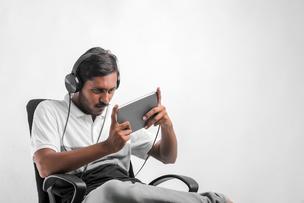 Jeune homme indien à l'aide de tablette sur fond blanc.