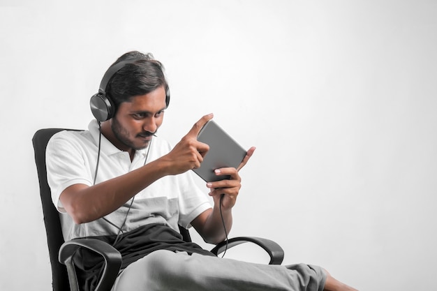 Jeune homme indien à l'aide de tablette sur fond blanc.