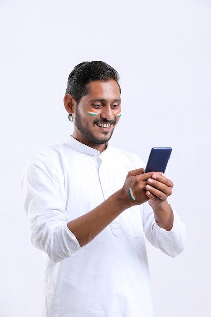 Jeune homme indien célébrant le jour de l'indépendance ou le jour de la république et utilisant un smartphone.