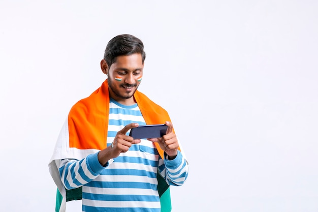 Jeune homme indien célébrant le jour de l'indépendance ou le jour de la république et utilisant un smartphone