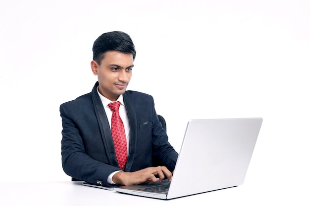 Jeune homme indien en costume et travaillant sur ordinateur portable au bureau