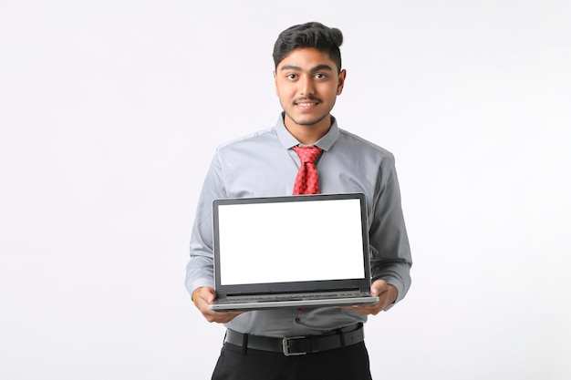 Jeune homme indien montrant un écran d'ordinateur portable sur fond blanc.