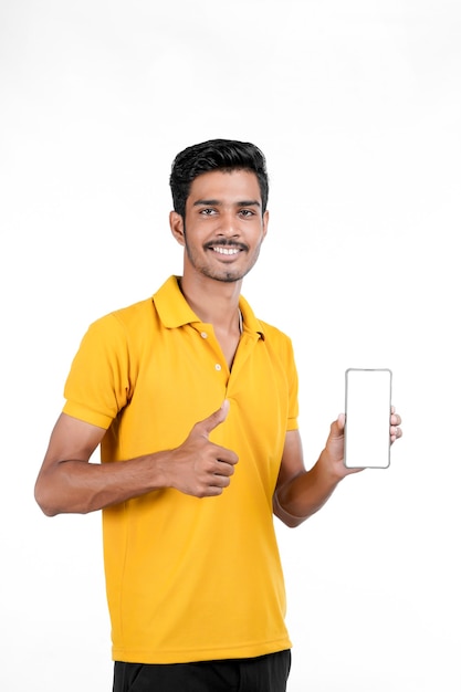 Jeune homme indien montrant smartphone sur fond blanc