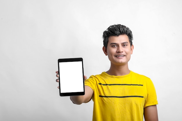 Jeune homme indien montrant la tablette sur fond blanc.