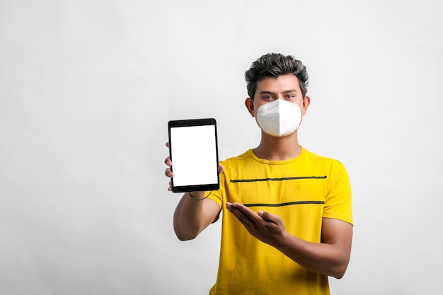 Jeune homme indien portant un masque et montrant une tablette