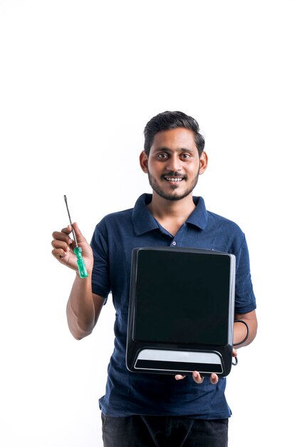 Jeune homme indien qui répare des ustensiles de cuisine électroniques tenant des outils et une cuisinière électrique à la main