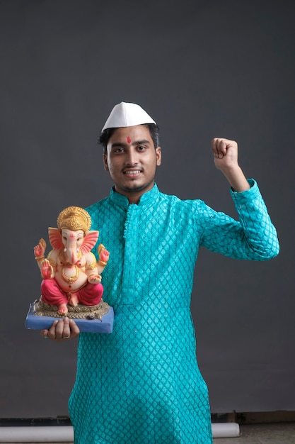 Jeune homme indien avec la sculpture du seigneur ganesha. célébrer le festival de ganesha.