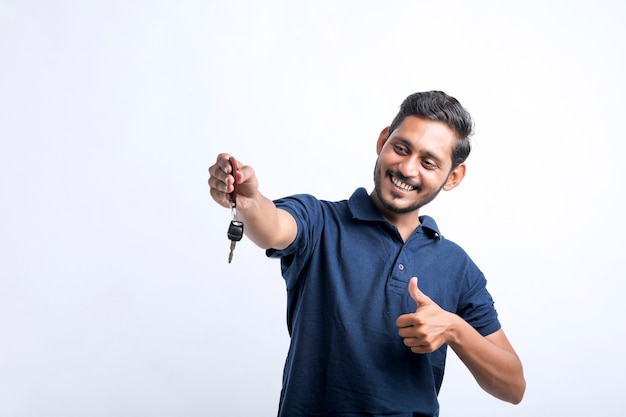 Jeune homme indien tenant la clé en main sur fond blanc.